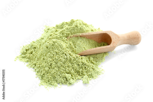 Heap of barley grass powder and wooden scoop on white background