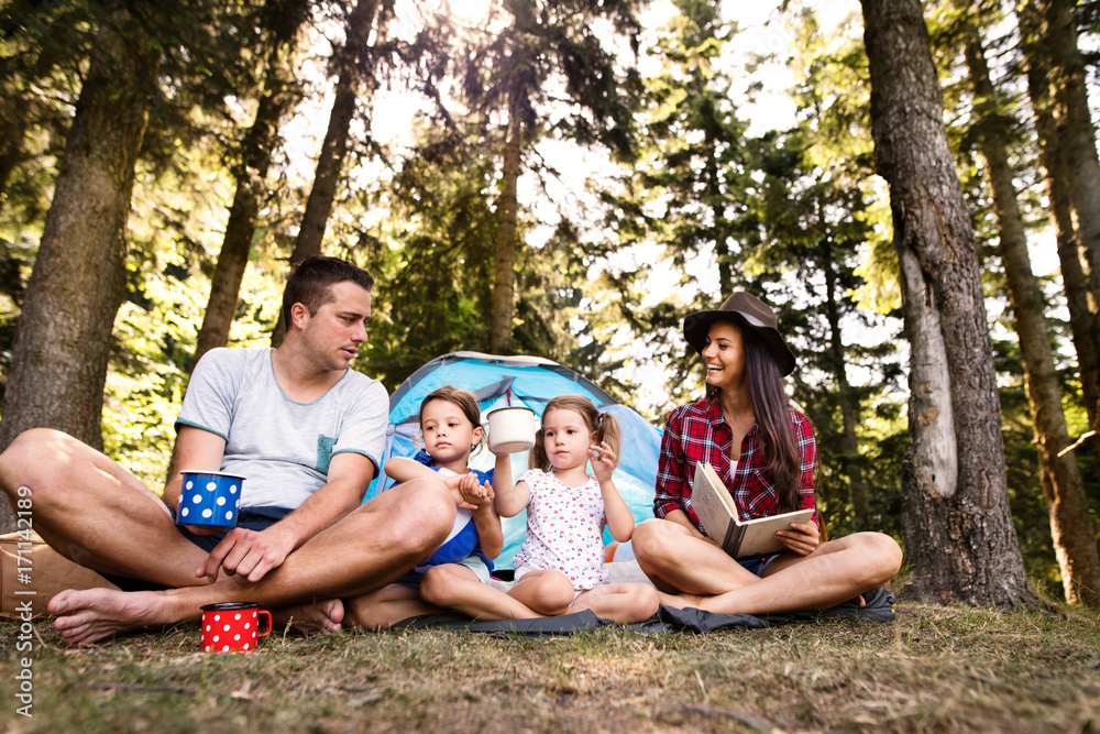 Beautiful young family with daughters camping in forest.