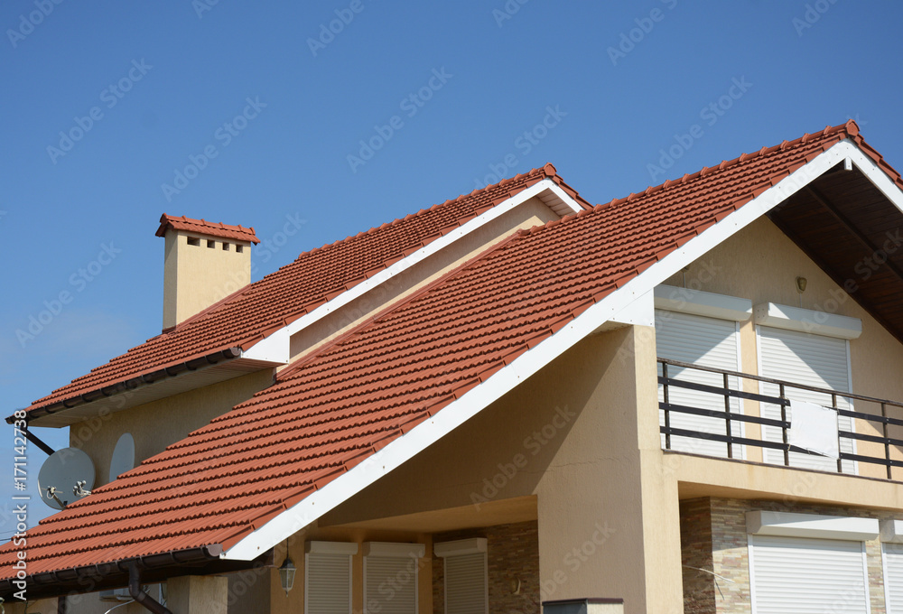 Cozy house with balcony, clay tiled roof and gable and valley type of roof construction. Building attic house construction with different types of roof designs