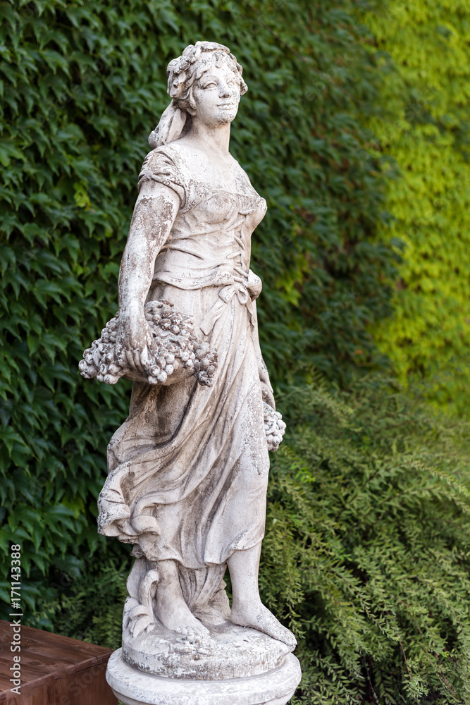 Old marble statue woman with basket of grapes in the park. Old marble statue woman with basket of grapes in the park.