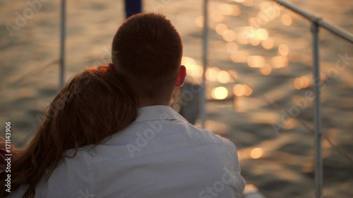 woman put head on men's shoulder while sitting on front of yacht watching at sea backside in slow motion