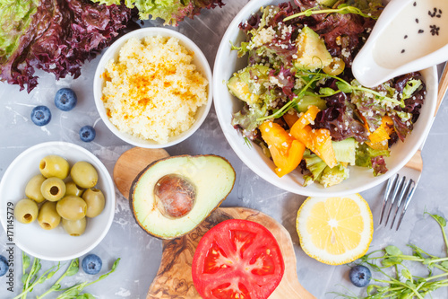 Bright colorful salad with couscous and vegetables, ingredients on the table, vegan lunch, top view.