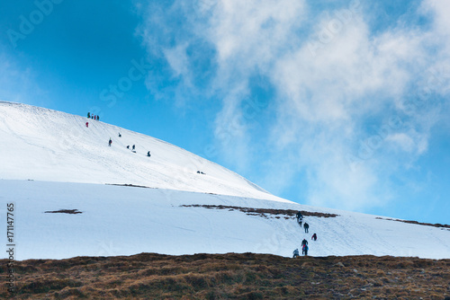 Tourists climbs for camping to the snow-capped mountain top. Concept theme: nature, weather, climbing, tourism, extreme, healthy lifestyle, adventures. Unrecognizable faces.