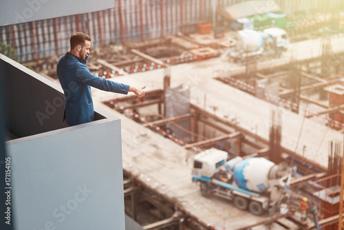 Top view of a professional senior engineer standing near constructiong site