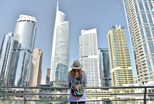 Photography Happy young traveler woman in big city Dubai in hat and travel bag