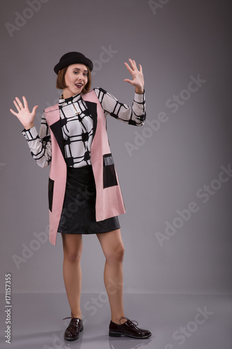 Portrait of extraordinary woman dressed in black hat and plaid shirt staying over gray background, The dancer stap showing hands photo