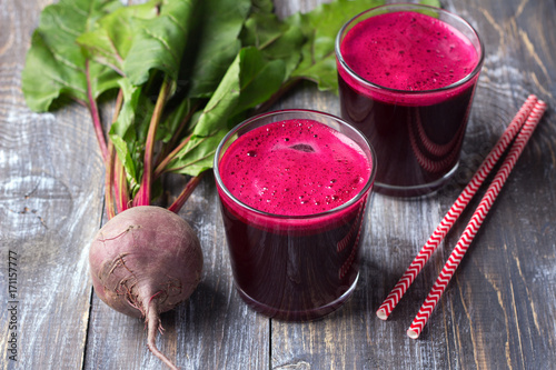 Fresh beet juice in glasses with a straw on a wooden background, selective focus. Healthy detox diet