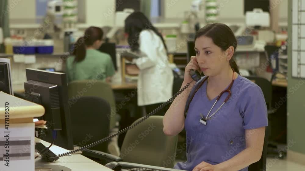Nurses answers phone in busy nurse's station in a modern hospital. Nurses answers phone in busy nurse's station in a modern hospital.