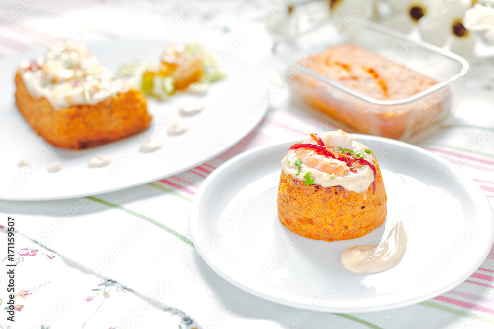 Traditional fish cake. Hake cake with tomato, shrimps and salad cream on Flower table cloth.