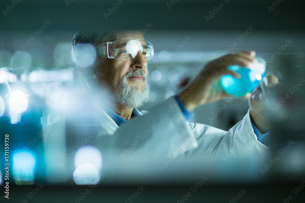 Fototapeta premium Senior male researcher carrying out scientific research in a lab (shallow DOF; color toned image)