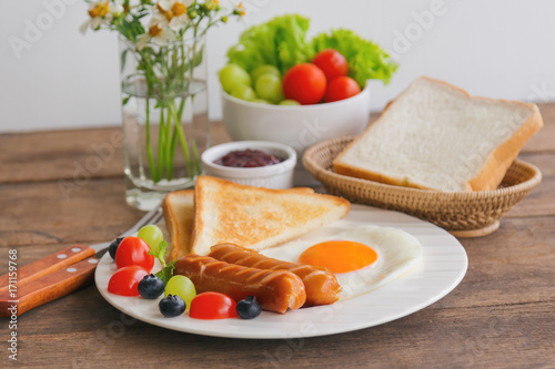 Homemade breakfast with sunny side up fried egg toast sausage fruits vegetable strawberry jam in side view with copy space.Delicious homemade american breakfast concept for background or wallpaper.