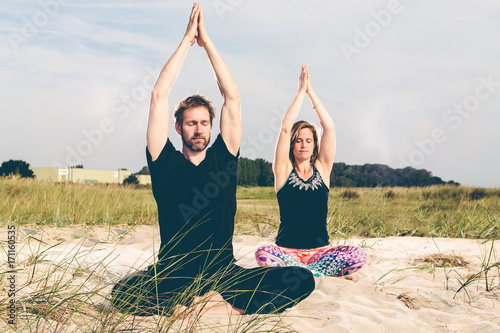 Junges Pärchen während seiner Yoga Übungen in den Dünen am Strand photo