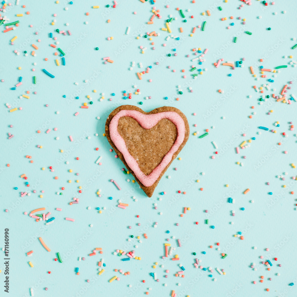Colorful hand made cookie and confetti on blue background. Flat lay, top view.
