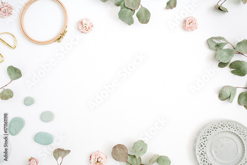 Flat lay border frame with eucalyptus branches, plate on white background. Top view floral background with space for text.