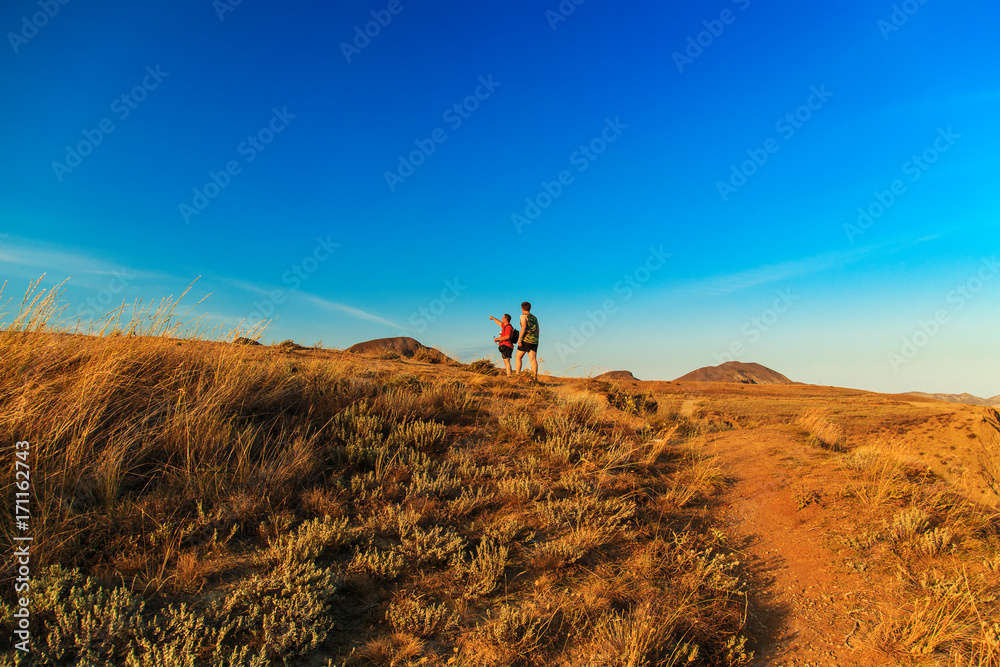 Two tourists walk across the hills.