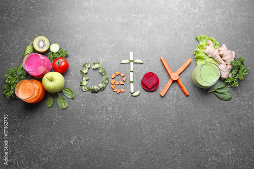Word DETOX made of vegetables, fresh juices in glasses and ingredients on grey background