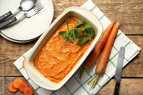 Baking dish with tasty carrot souffle on wooden table