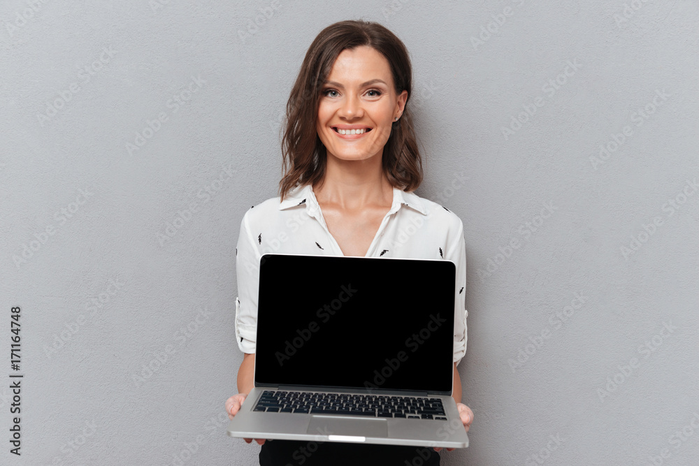 Happy woman in business clothes showing blank laptop computer screen Happy woman in business clothes showing blank laptop computer screen