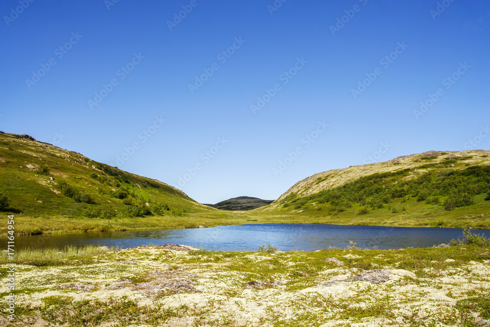 Two mountain hills behind a small clean lake