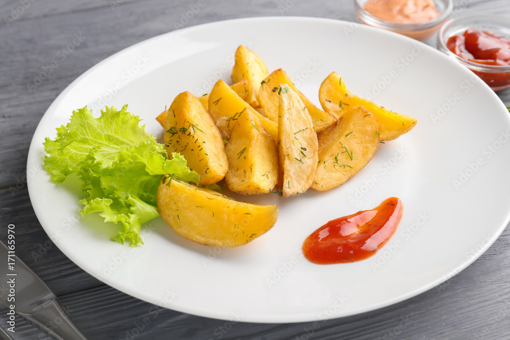 Plate with delicious baked potato wedges and sauce on table Plate with delicious baked potato wedges and sauce on table