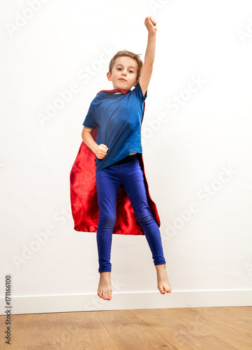 Fototapeta Naklejka Na Ścianę i Meble -  Powerful superhero boy with a cape jumping high, reaching freedom