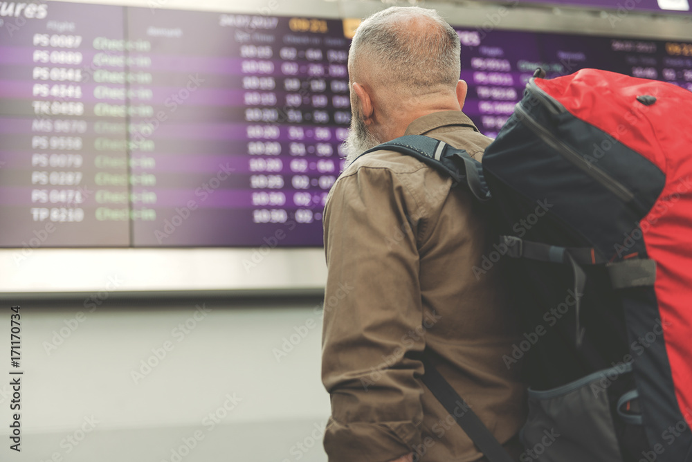 Unshaven pensioner watching at board with information Unshaven pensioner watching at board with information