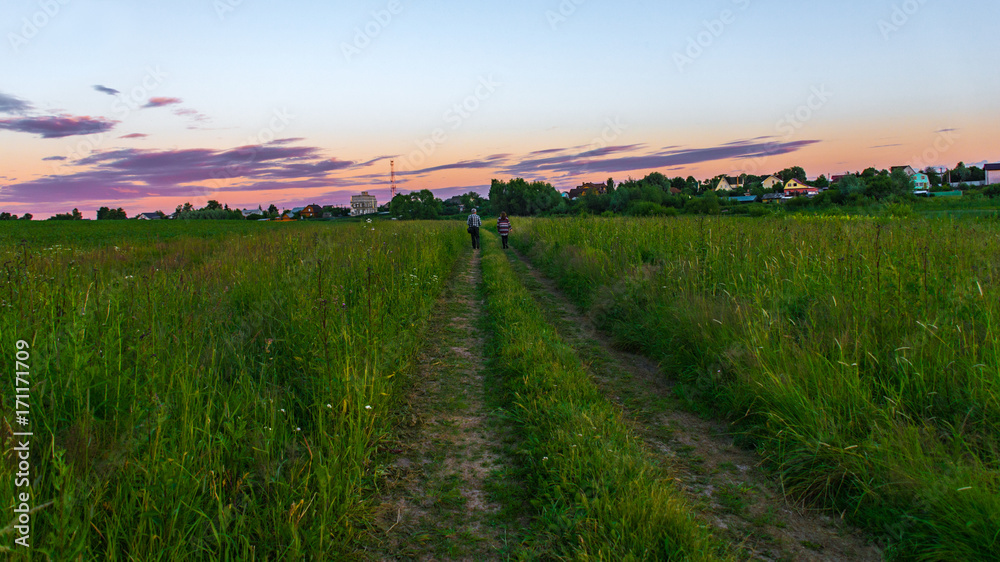 Couple walking on a dirt road in the evening time