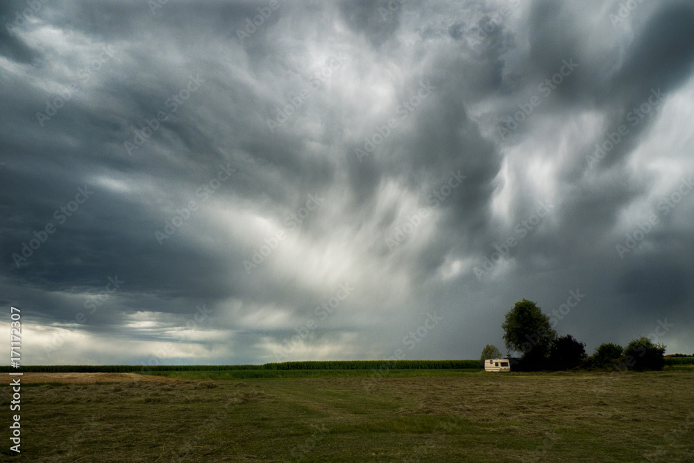 Dramatic dark clouds of thunderstorm over a field in the countryside Dramatic dark clouds of thunderstorm over a field in the countryside