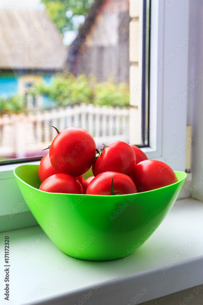 ripe tomatoes with ponytails in bright light green bowl standing on the windowsill ripe tomatoes with ponytails in bright light green bowl standing on the windowsill
