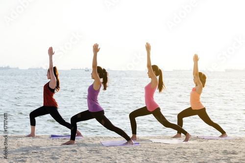 Group of young healthy women practicing yoga on the beach, healthy lifestyles, wellness, well being