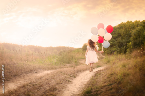 Little girl with colorful balloons at the meadow - Back view