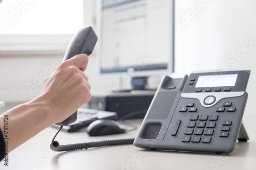 Telefon auf Schreibtisch, Griff zum Hörer