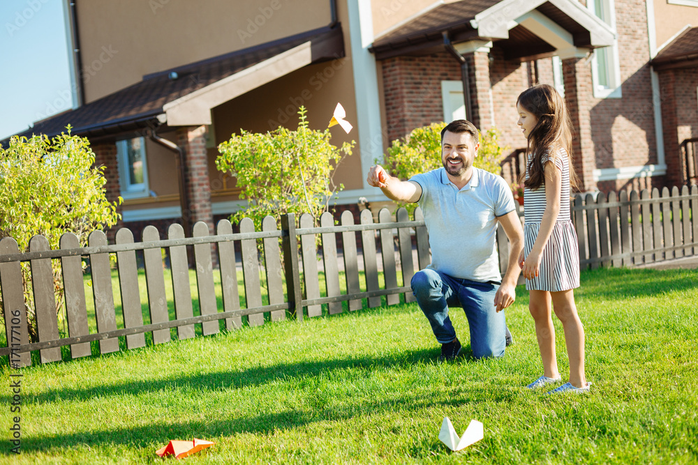 Happy father launching a paper plane in backyard