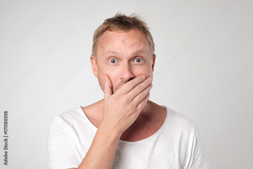 young caucasian man shows sign hand gesture holding finger on lips. young caucasian man shows sign hand gesture holding finger on lips.