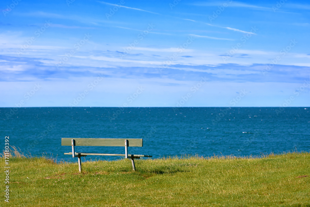 Empty bench on the shore of the ocean on a summer day
