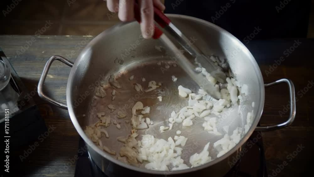 Chef's male hand stirring the chopped onions in a saucepan and frying with vegetable oil. 4K Chef's male hand stirring the chopped onions in a saucepan and frying with vegetable oil. 4K