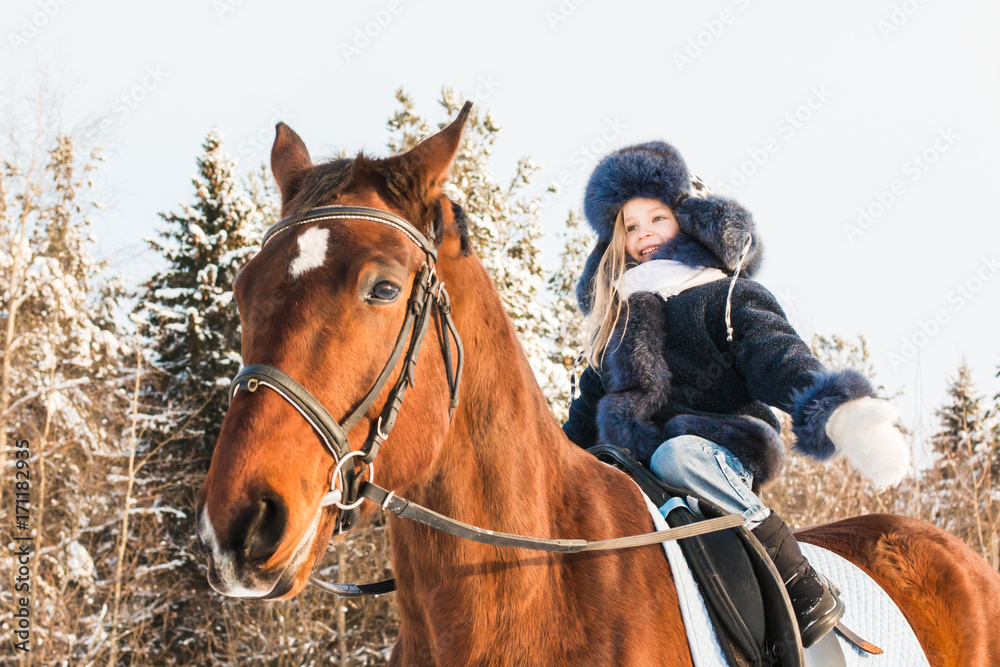 Fototapeta premium Small girl and horse in a winter