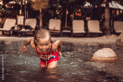 Fototapeta Naklejka Na Ścianę i Meble -  little girl is splashing in the pool