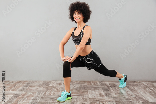 Full length picture of pleased sports woman stretching