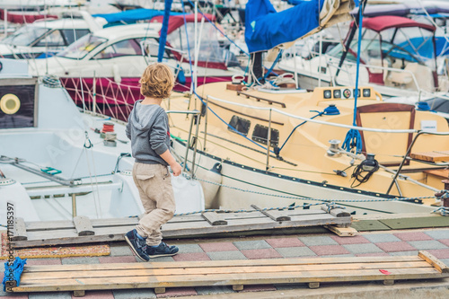 Cute blond boy looking at yachts and sailboats photo