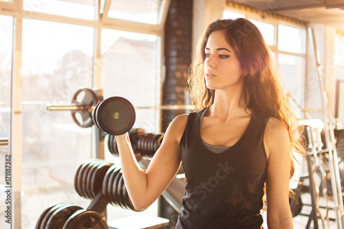 Portrait of athletic young woman training with a weight in the gym
