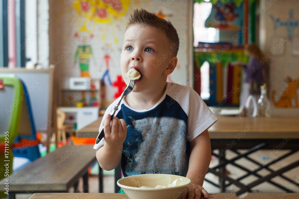Cute toddler boy eating in indoors cafe Cute toddler boy eating in indoors cafe