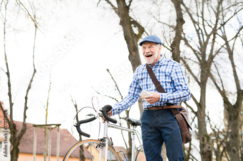 Senior man with smartphone and bicycle in town.