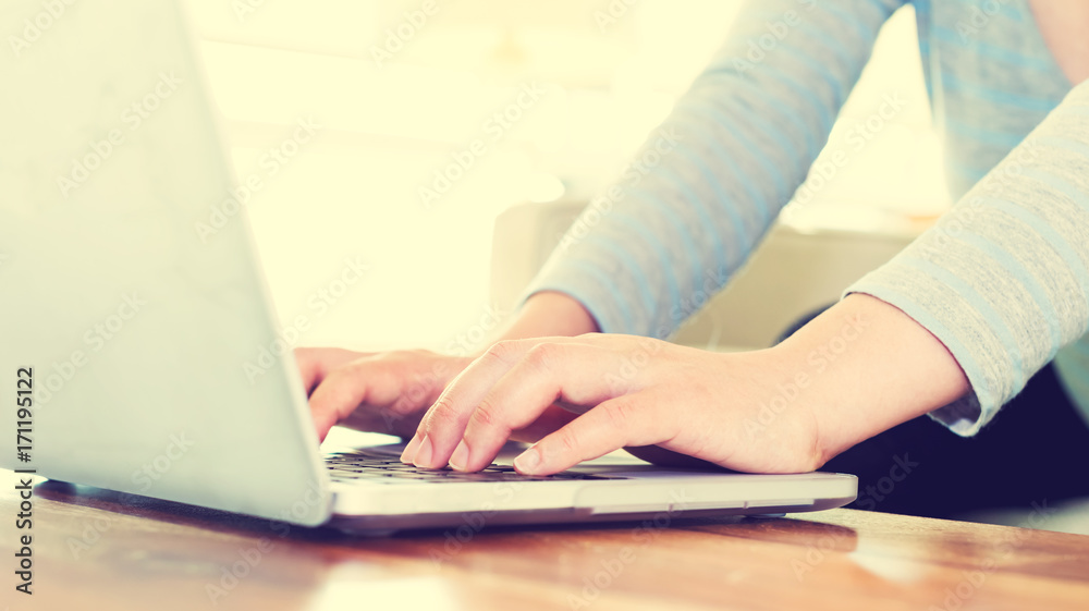 Fototapeta premium Woman working on a laptop in brightly lit room
