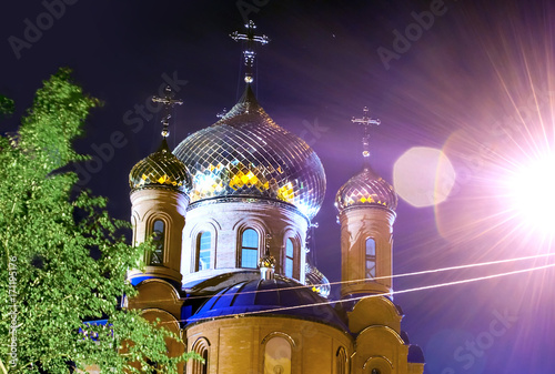 The Church of THE HOLY APOSTLES AND THE GOSPEL JOHN OF BOGHOSLOV in the park at autumn night. Pokrov town, Ukraine, 2017. Lighted golden domes photo