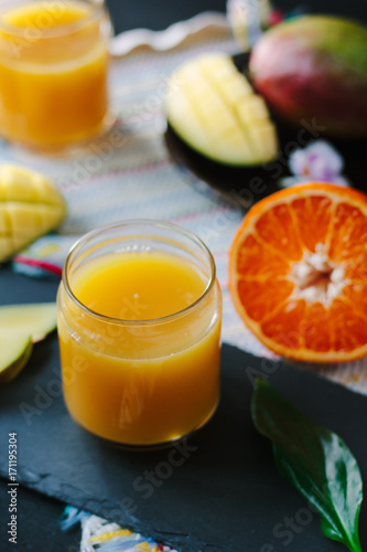 Fresh mango and orange detox drink over black slate.
