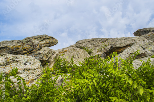 The top of one of the red sandstones with its numerous caves under the cloudy sky. © Vitalii