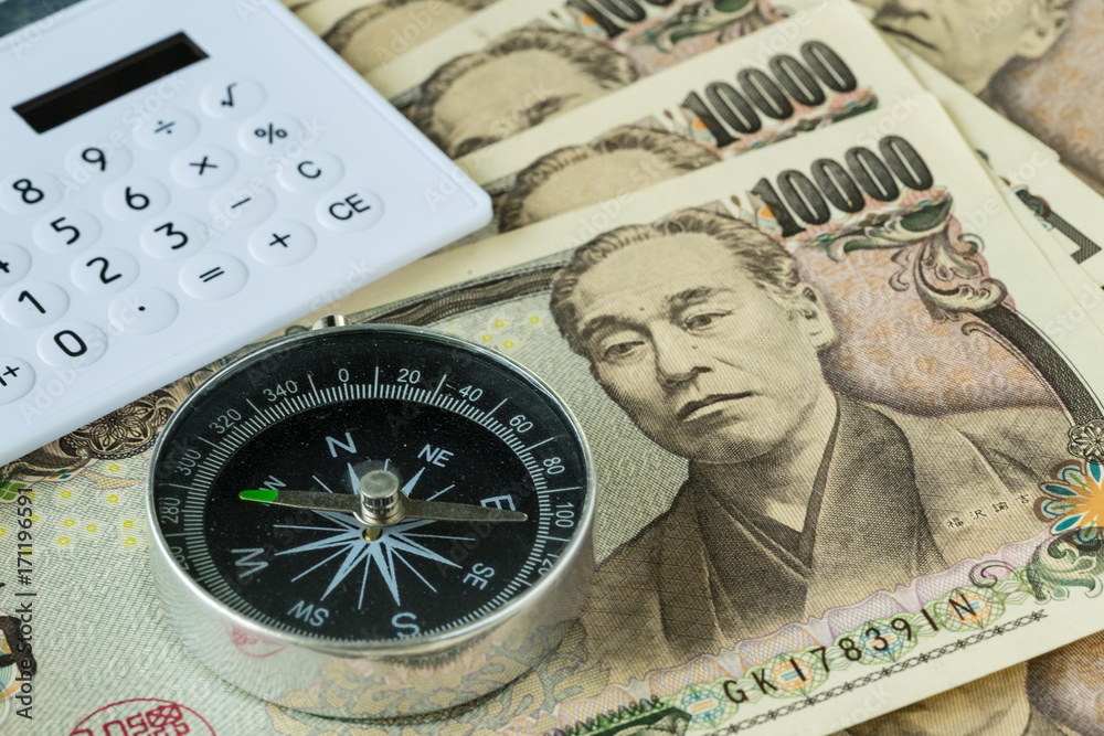 Compass and calculator on pile of japanese yen banknotes as financial safe haven or tax concept Compass and calculator on pile of japanese yen banknotes as financial safe haven or tax concept
