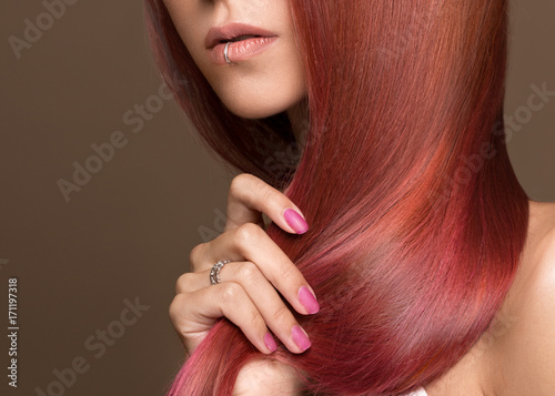 Beautiful pink-haired girl in move with a perfectly smooth hair, and classic make-up. Beauty face. Picture taken in the studio.