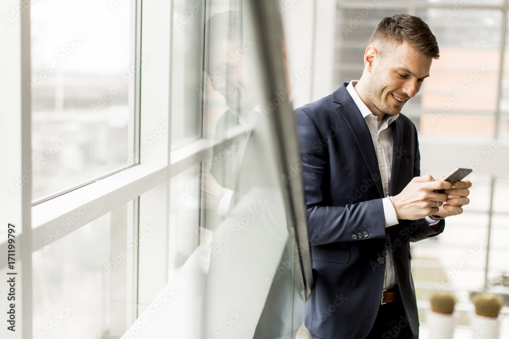 Elegant young businessman using cellphone on staircase in office Elegant young businessman using cellphone on staircase in office
